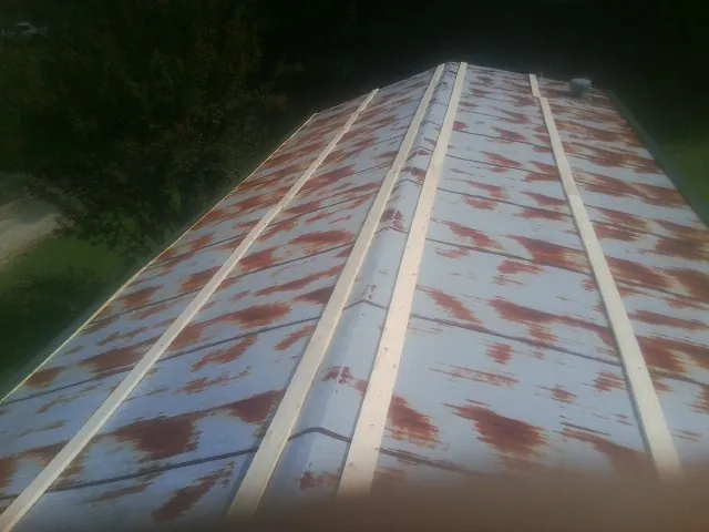 Rusted metal roof panels with new wood purlins before replacement — Storm Damage Roof Repair in Panora by Roofing Brothers