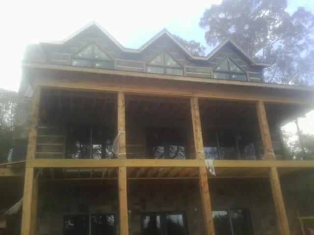 Dormers and porch framing on a large log home under construction — Roof Coating work by our crew in Panora