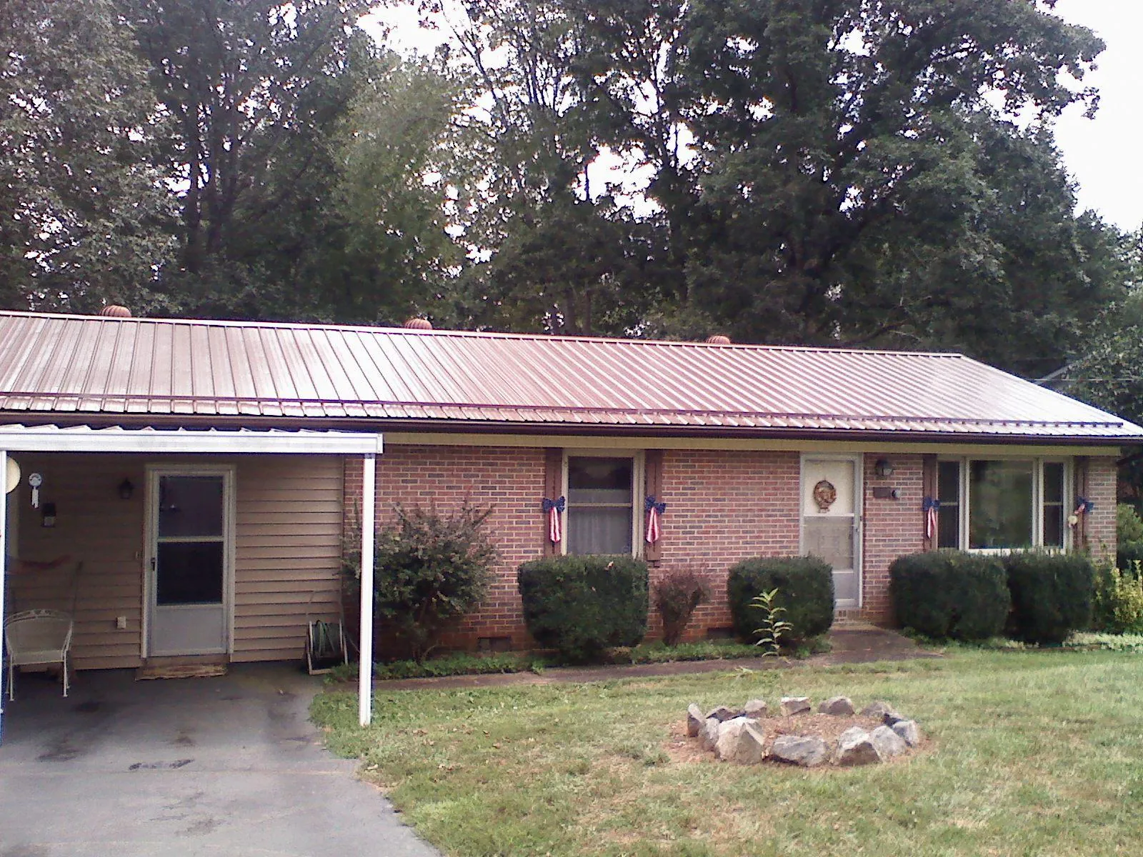Bronze metal roof and carport on a brick ranch home — Roof Repair work by our crew in Panora
