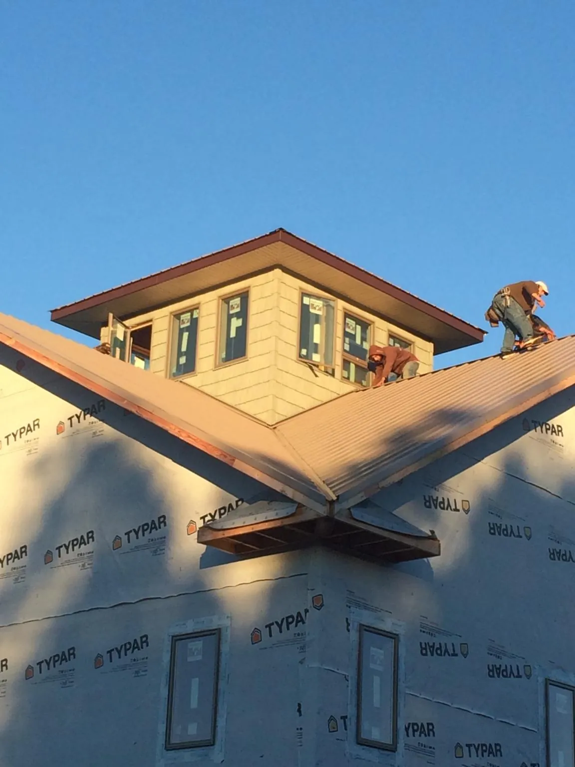 Roofers working around a rooftop cupola on a new metal roof at sunset — Roof Waterproofing in Panora by Roofing Brothers